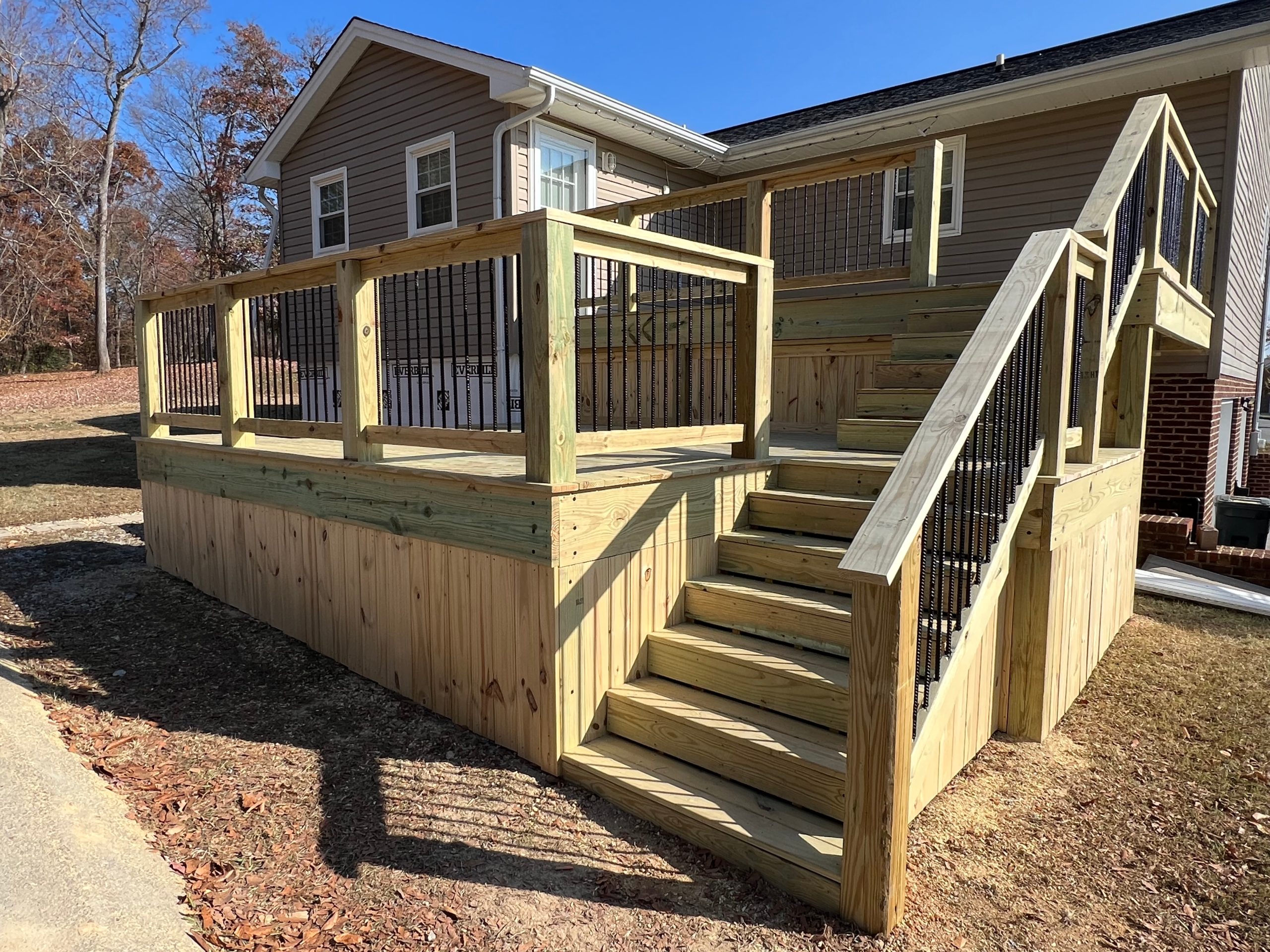 Wood deck with cedar picket underpinning; black rebar spindles; stairs.